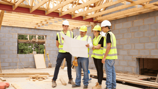 

Trois apprentis travaillant avec un entrepreneur à l’intérieur d’une maison en construction