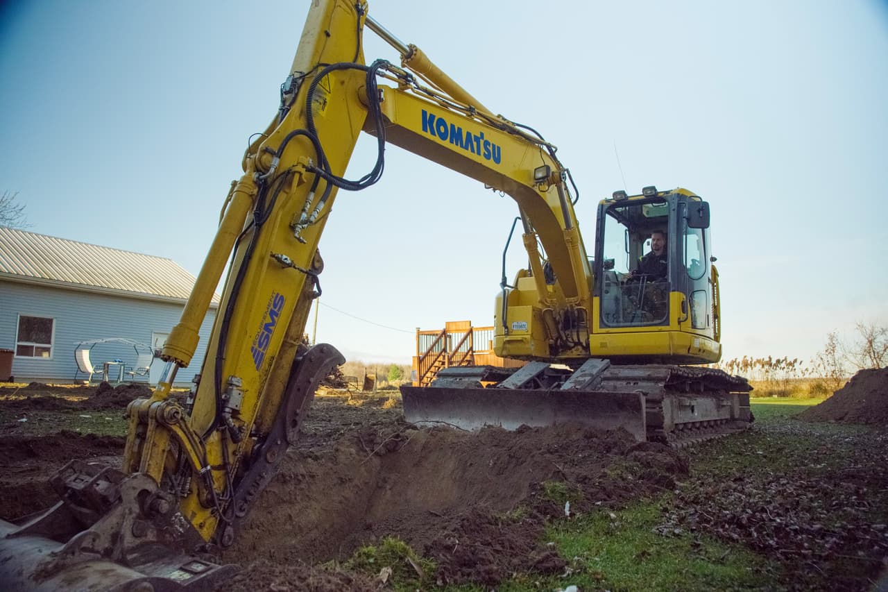 Pelle mécanique Komatsu creusant une tranchée sur un terrain résidentiel en préparation de travaux d'excavation