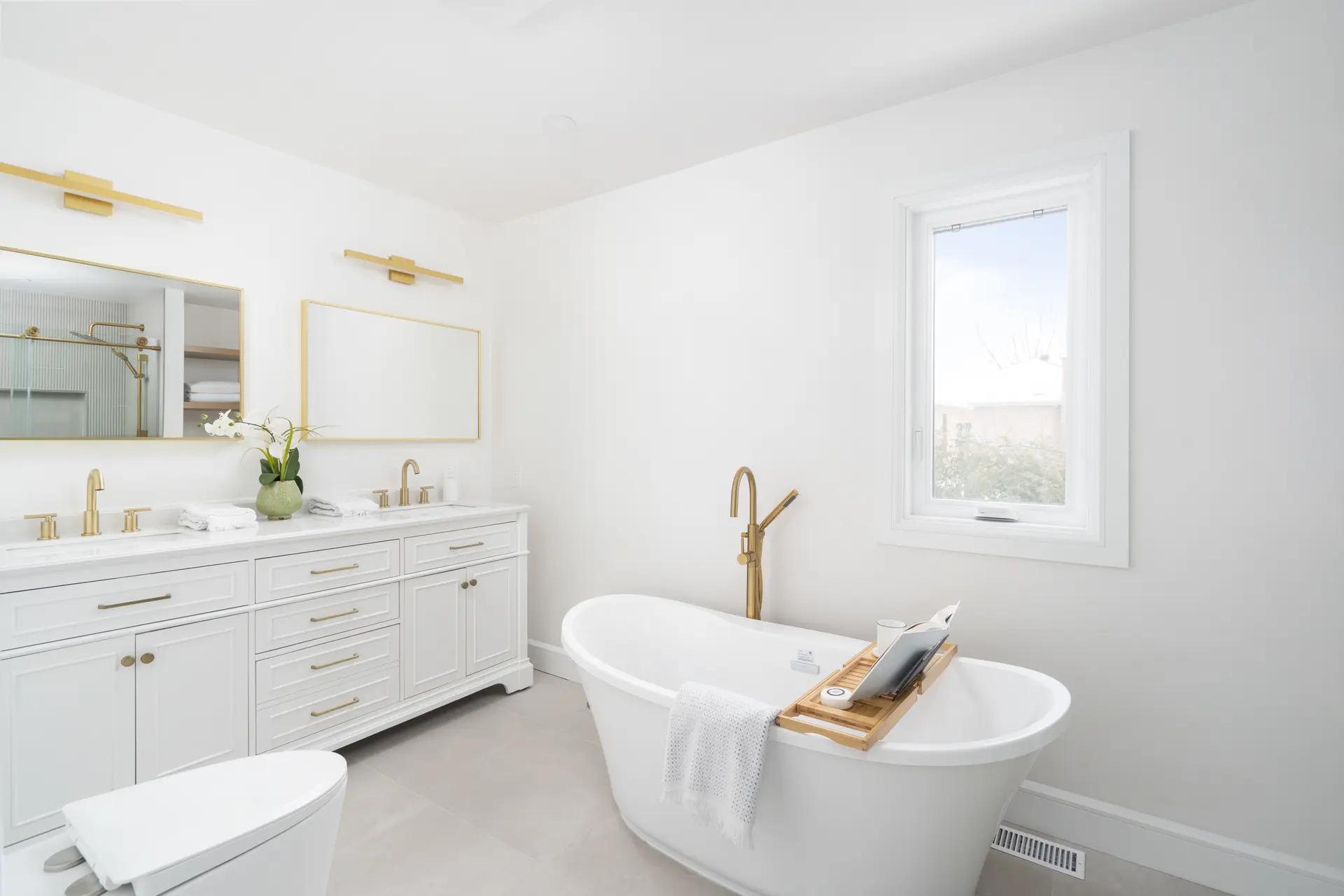 Salle de bain moderne et lumineuse avec une baignoire autoportante et des finitions en laiton