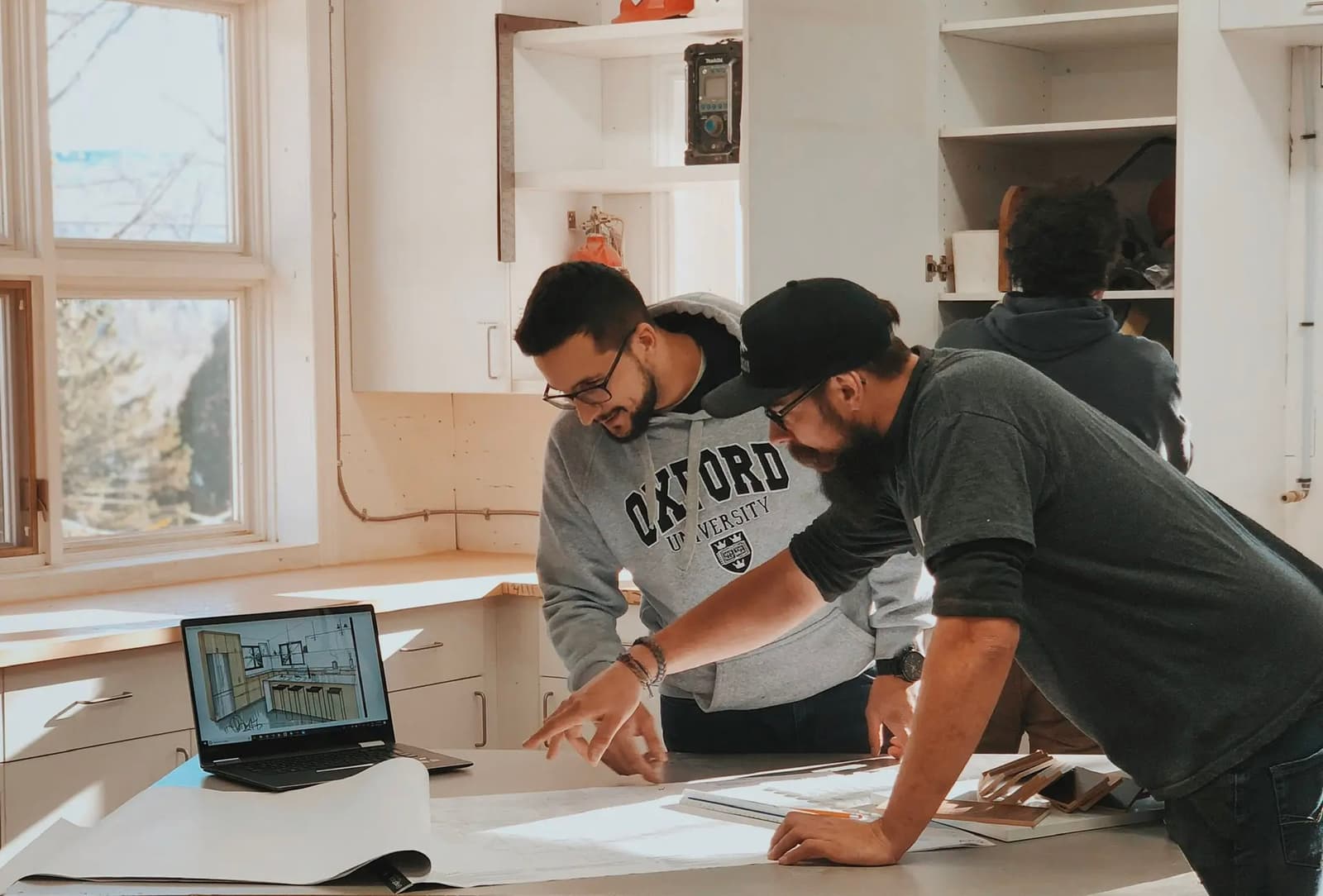 Des professionnels collaborent dans un atelier sur la conception d'un projet architectural avec plans et ordinateur portable.