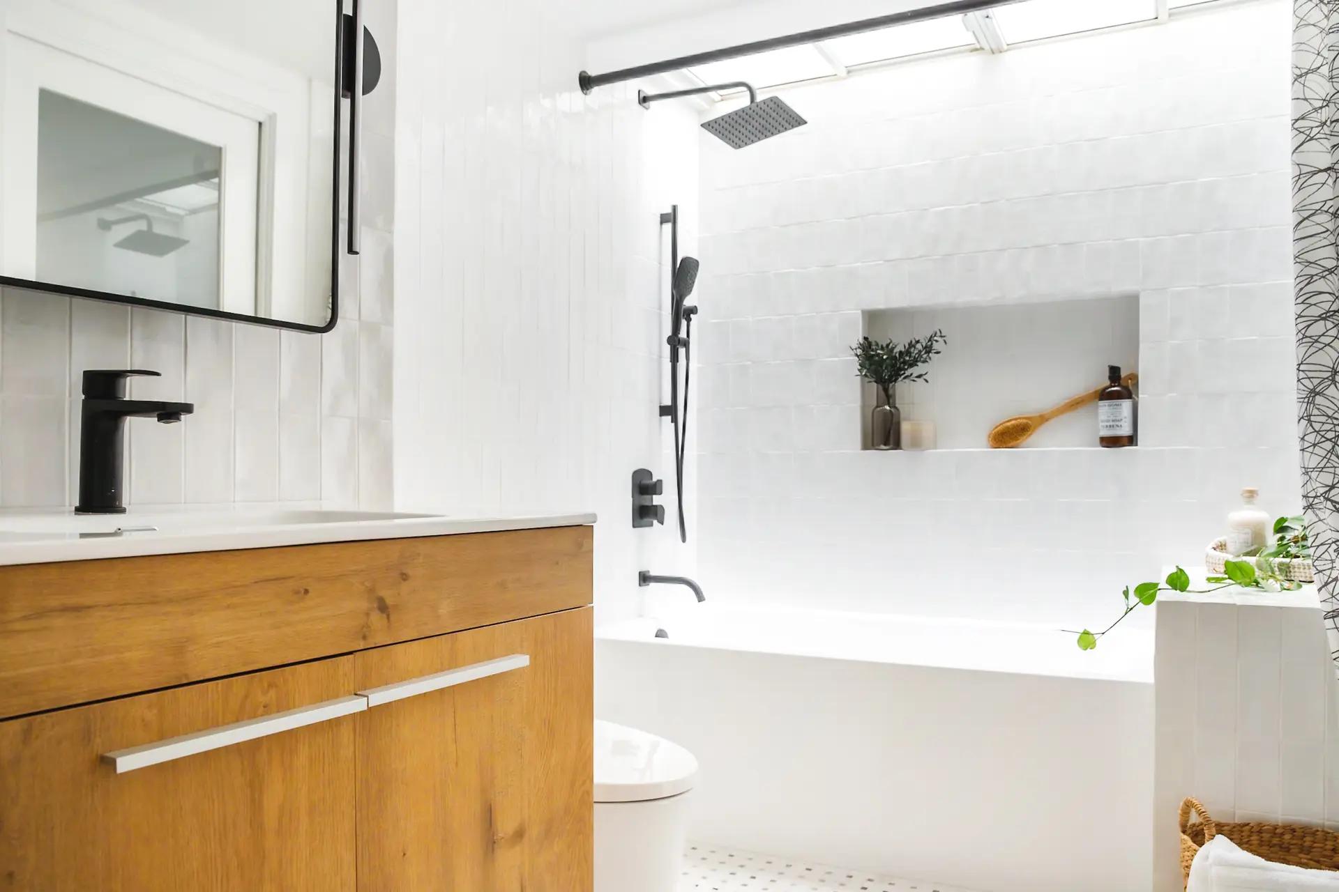 Salle de bain lumineuse avec une baignoire blanche, une douche équipée d'une pomme de douche pluie et un meuble en bois sous-vasque.