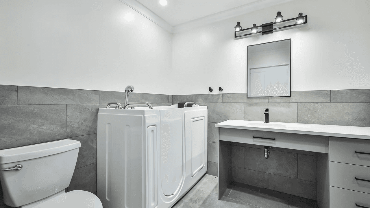 Kim Lacharité designer d'intérieur - Salle de bain moderne avec bain thérapeutique sécurisé, lavabo suspendu et céramique grise murale