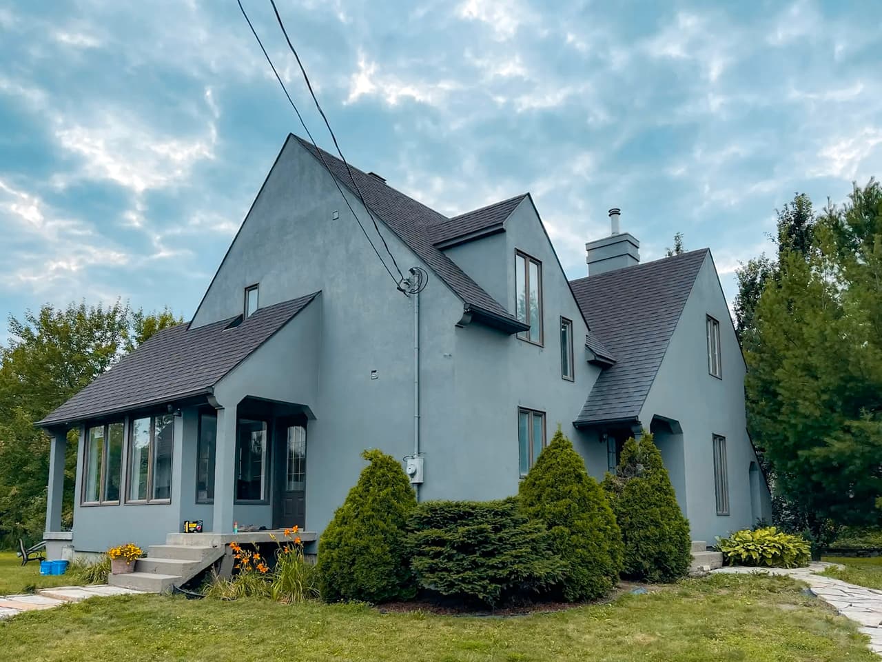 Maison moderne bleue avec revêtement extérieur uniforme, accents de bois en pignon et balcon avec garde-corps en bois