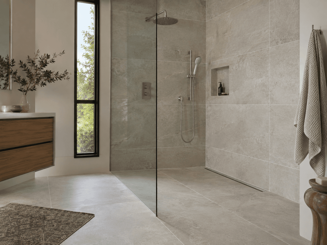 Salle de bain moderne avec grande douche à l’italienne vitrée, carrelage beige grand format, douche pluie, niche murale et meuble-lavabo en bois