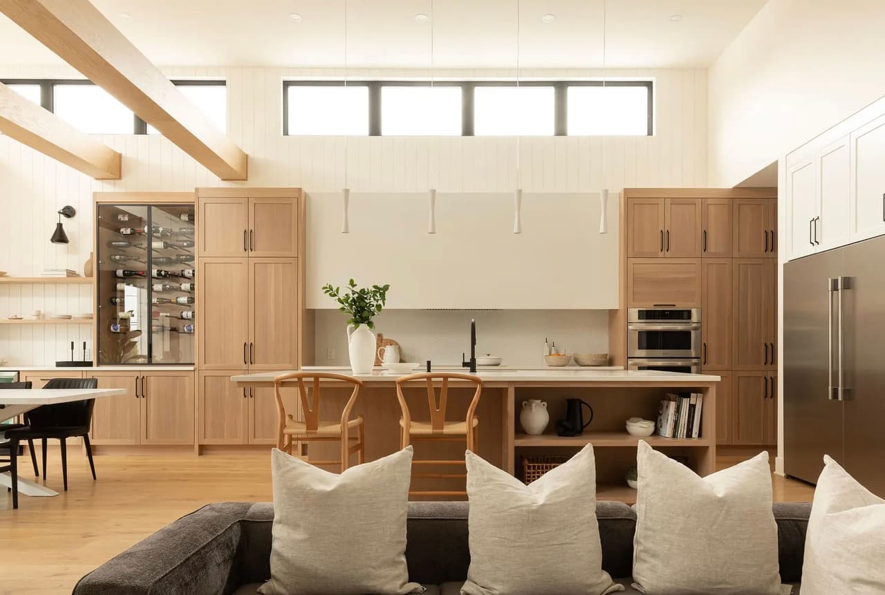 Cuisine moderne en bois clair avec ilot central, grande armoire à vin, électroménagers intégrés et design épuré