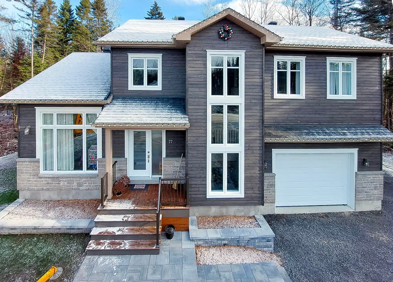 Maison unifamiliale moderne avec revêtement extérieur en bois, garage intégré et aménagement paysager en façade