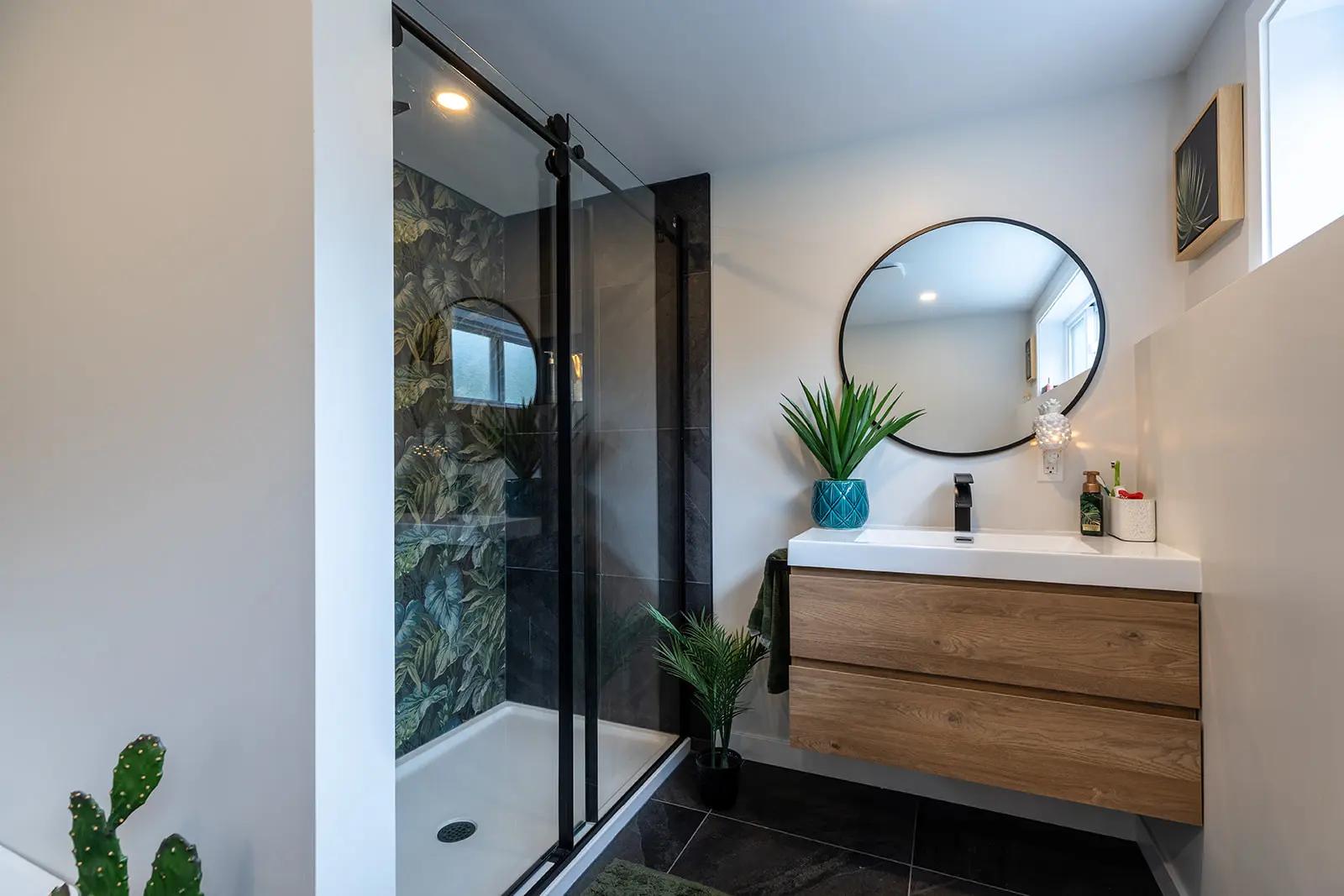 Salle de bains moderne et lumineuse avec une douche à l'italienne, un meuble-lavabo en bois et des plantes vertes.