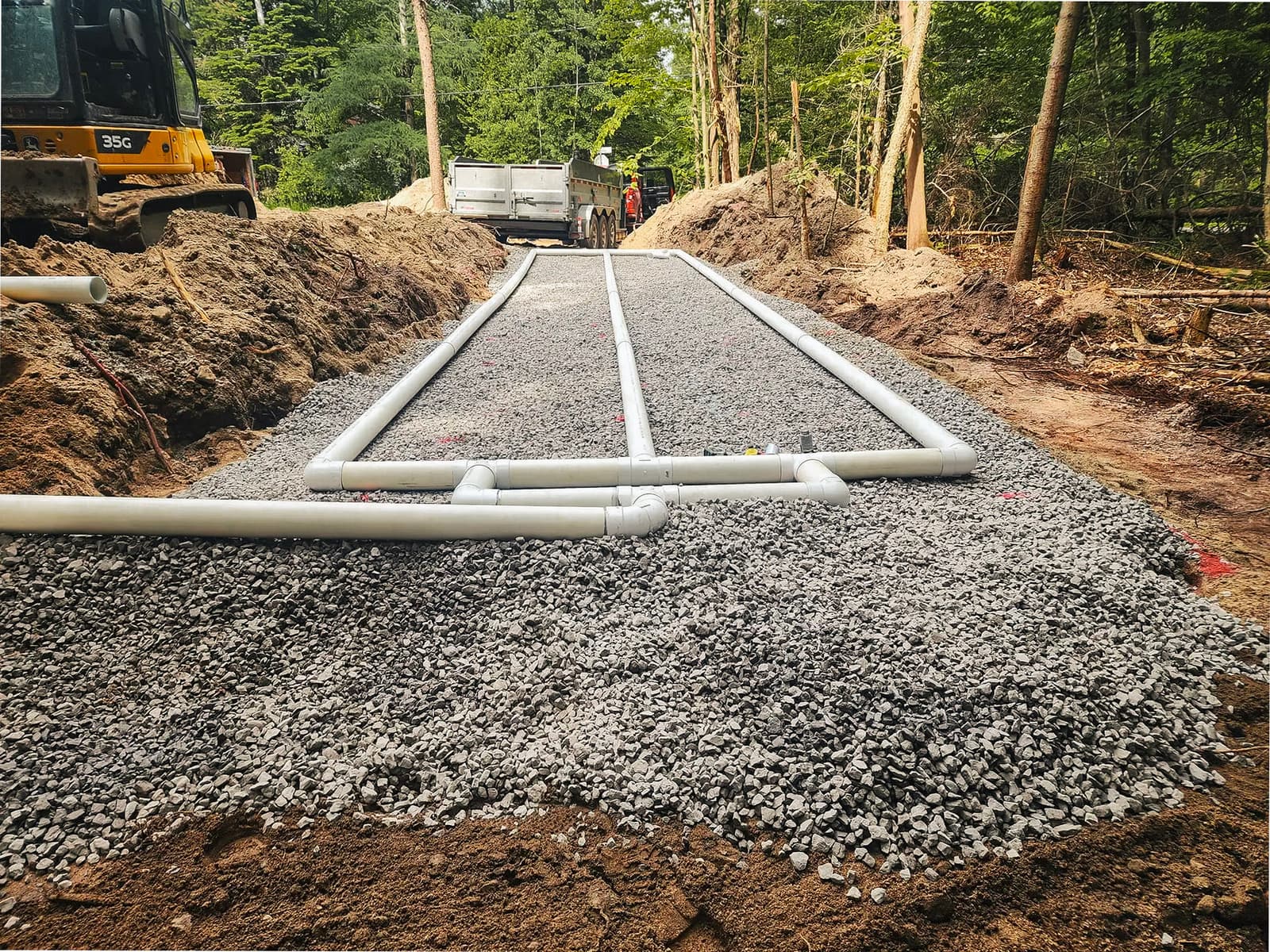 Installation d'un système septique avec tuyaux en PVC et gravier pour drainage.