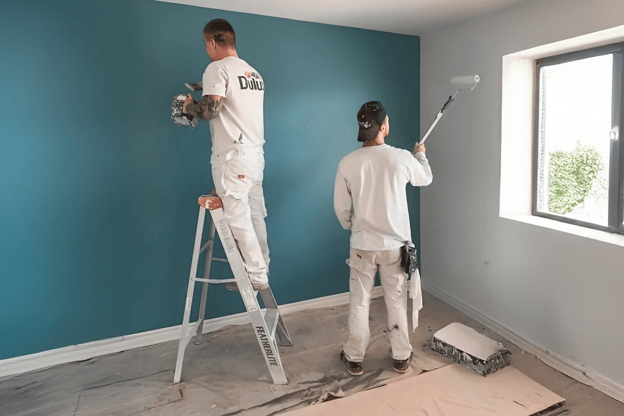 Travaux de peinture intérieure réalisés par des peintres professionnels appliquant une peinture bleue sur un mur pour une rénovation moderne.
