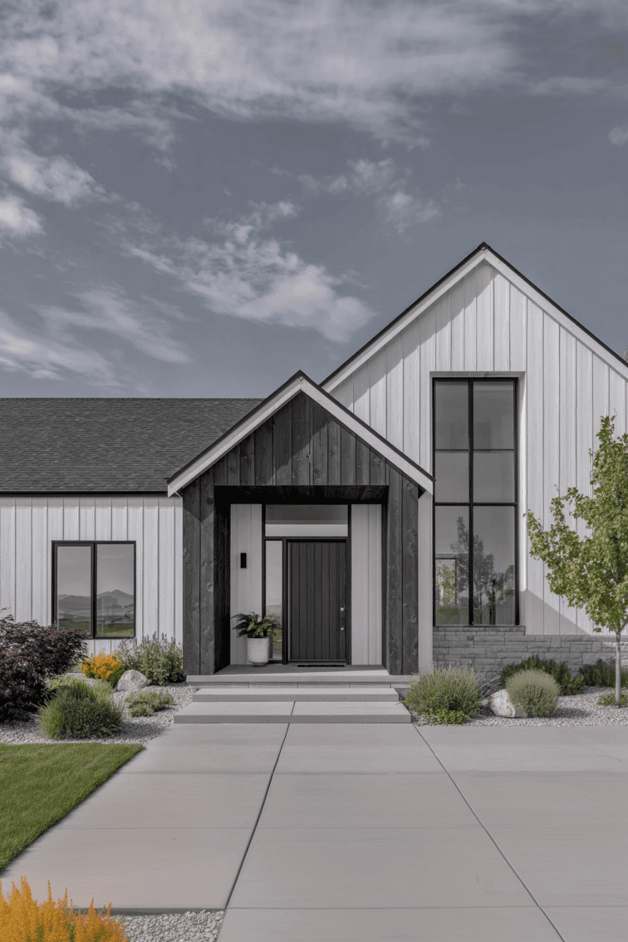 Façade de maison moderne avec revêtement vertical blanc et bois foncé, entrée avec escalier en béton et aménagement paysager minimaliste