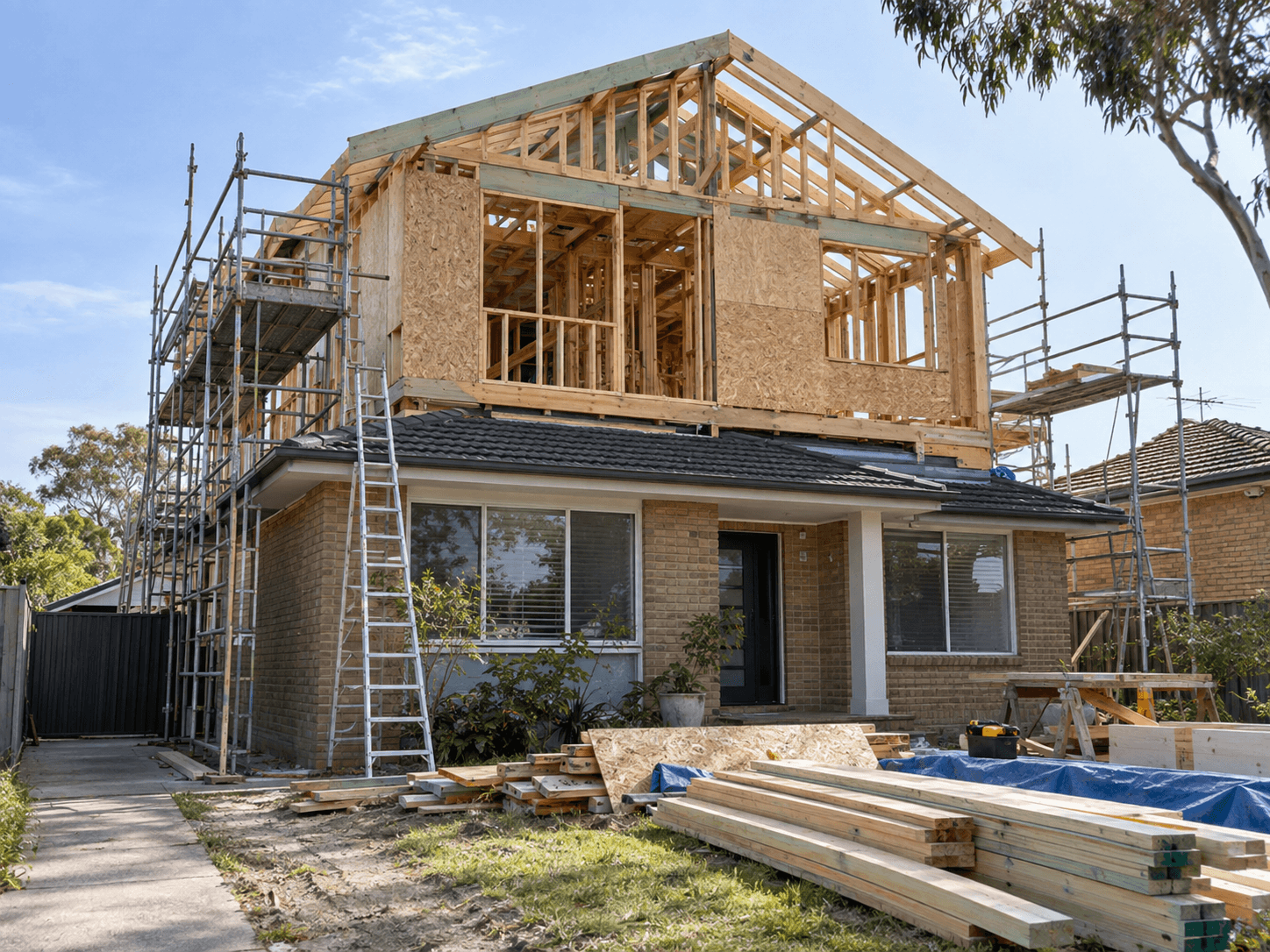 Surélévation de maison en construction avec charpente en bois apparente, panneaux structuraux, toiture en cours de montage et échafaudages autour du bâtiment