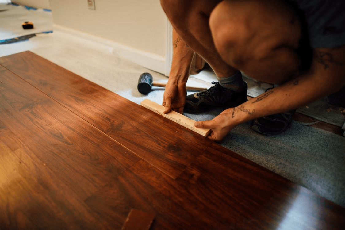 Installation professionnelle d’un plancher de bois brun dans une pièce résidentielle lors de travaux de rénovation intérieure.