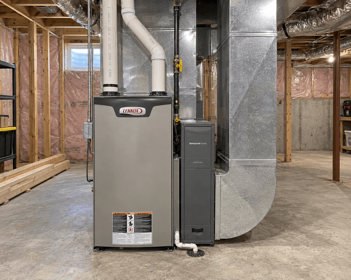 Sous-sol non fini avec fournaise résidentielle, système de chauffage central, conduits de ventilation métalliques, tuyauterie et isolation murale apparente.
