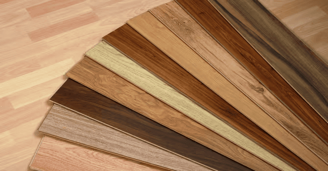 Échantillons de revêtements de plancher en bois disposés en éventail, présentant différentes essences, teintes et finitions, du chêne clair au brun foncé, pour un projet de rénovation intérieure