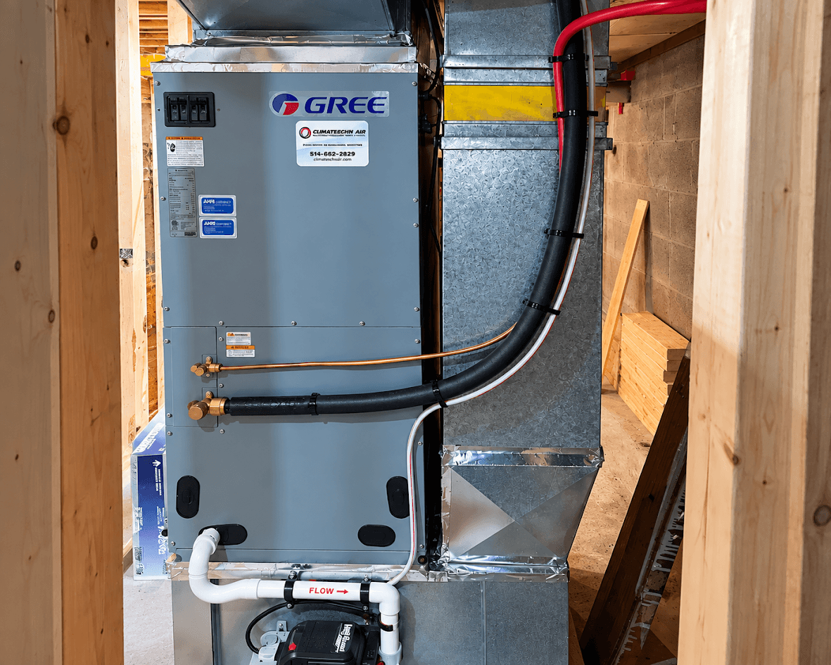 Système central de chauffage et climatisation installé dans un sous-sol en construction, avec unité Gree, conduits métalliques, tuyaux isolés et évacuation de condensat.