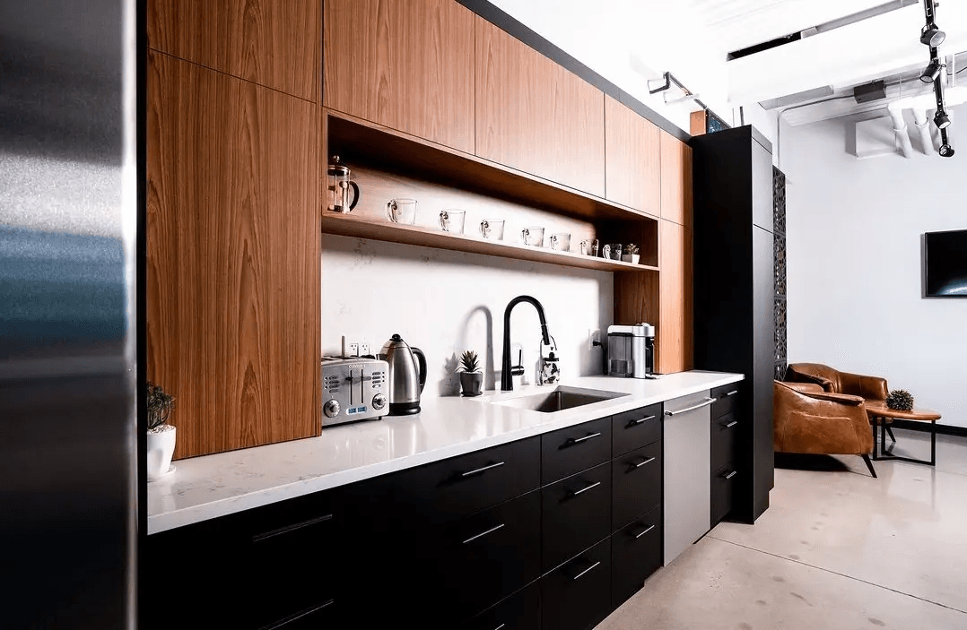Cuisine contemporaine avec armoires en bois sur mesure, cabinets noirs, comptoir blanc, évier intégré et espace café dans un intérieur moderne