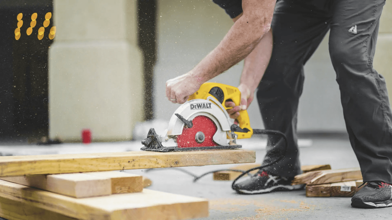 Travailleur utilisant une scie circulaire pour découper une planche de bois sur un chantier.
