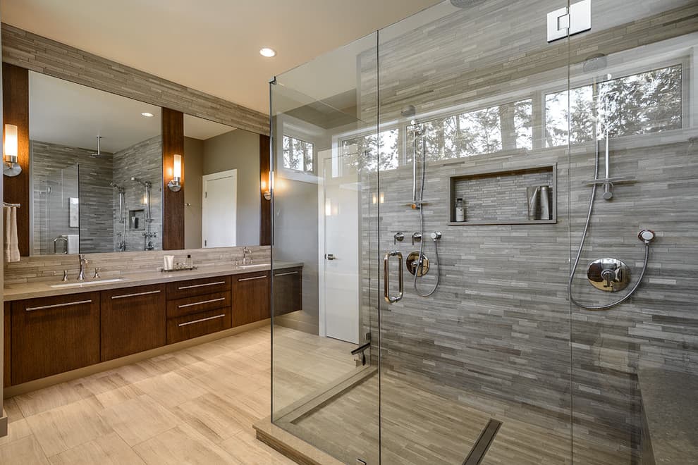 Salle de bain de luxe avec une grande douche vitrée, des murs en pierre grise texturée et une vanité en bois foncé