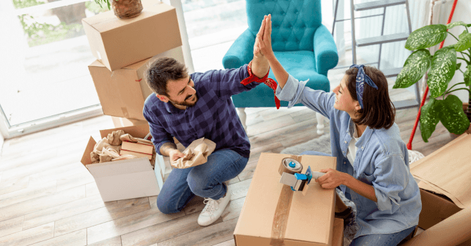 Un homme et un femme qui se félicite avec un "high five" entourés de boîtes de&nbsp; déménagement.