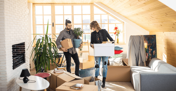 Un homme et une femme en plain déménagement encombrés de boîtes dans le salon.