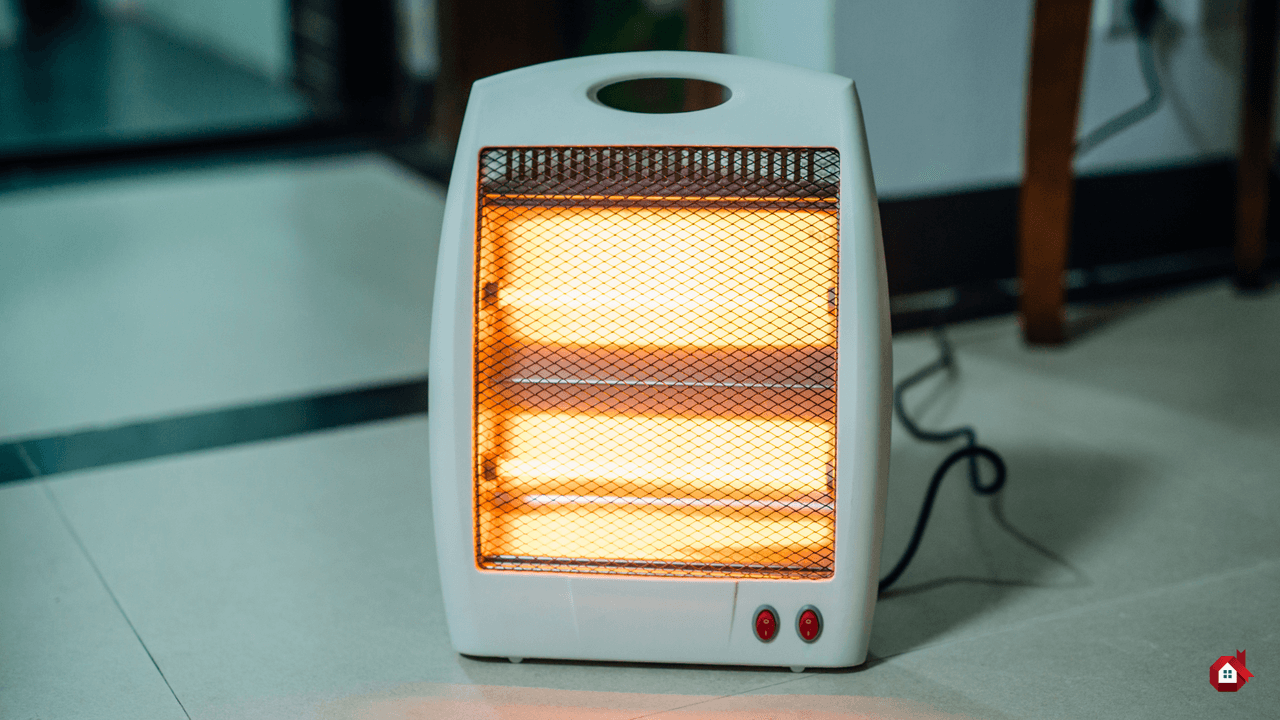 Chaufferette électrique portable blanche allumée posée sur un sol carrelé, montrant des tubes halogènes radiants orange et brillants
