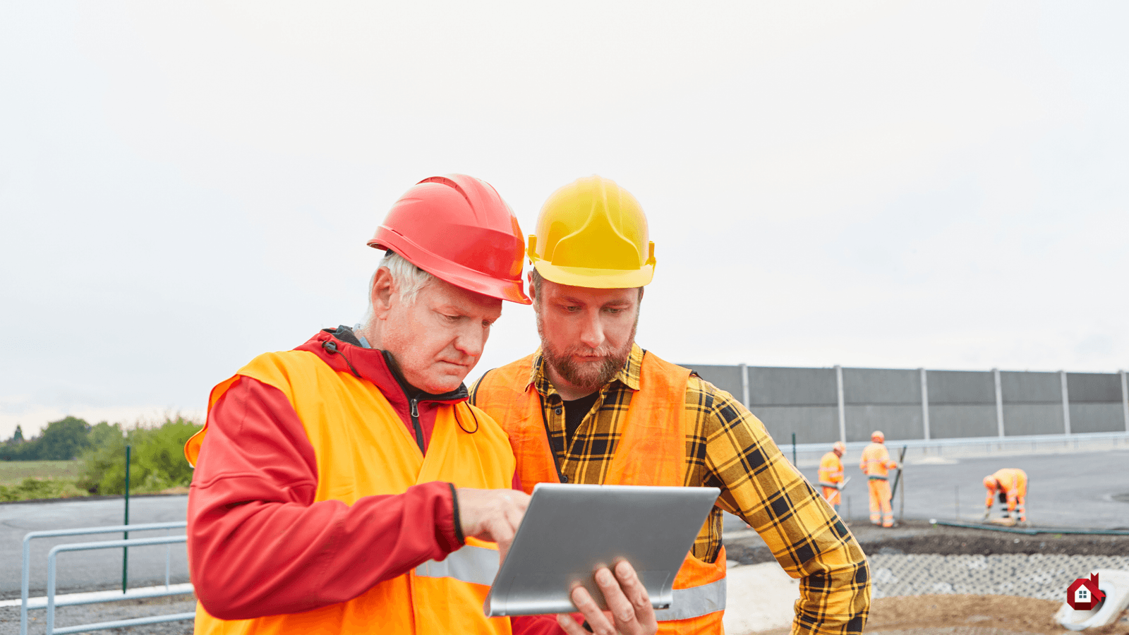 Deux travailleurs de la construction discutant devant un ordinateur