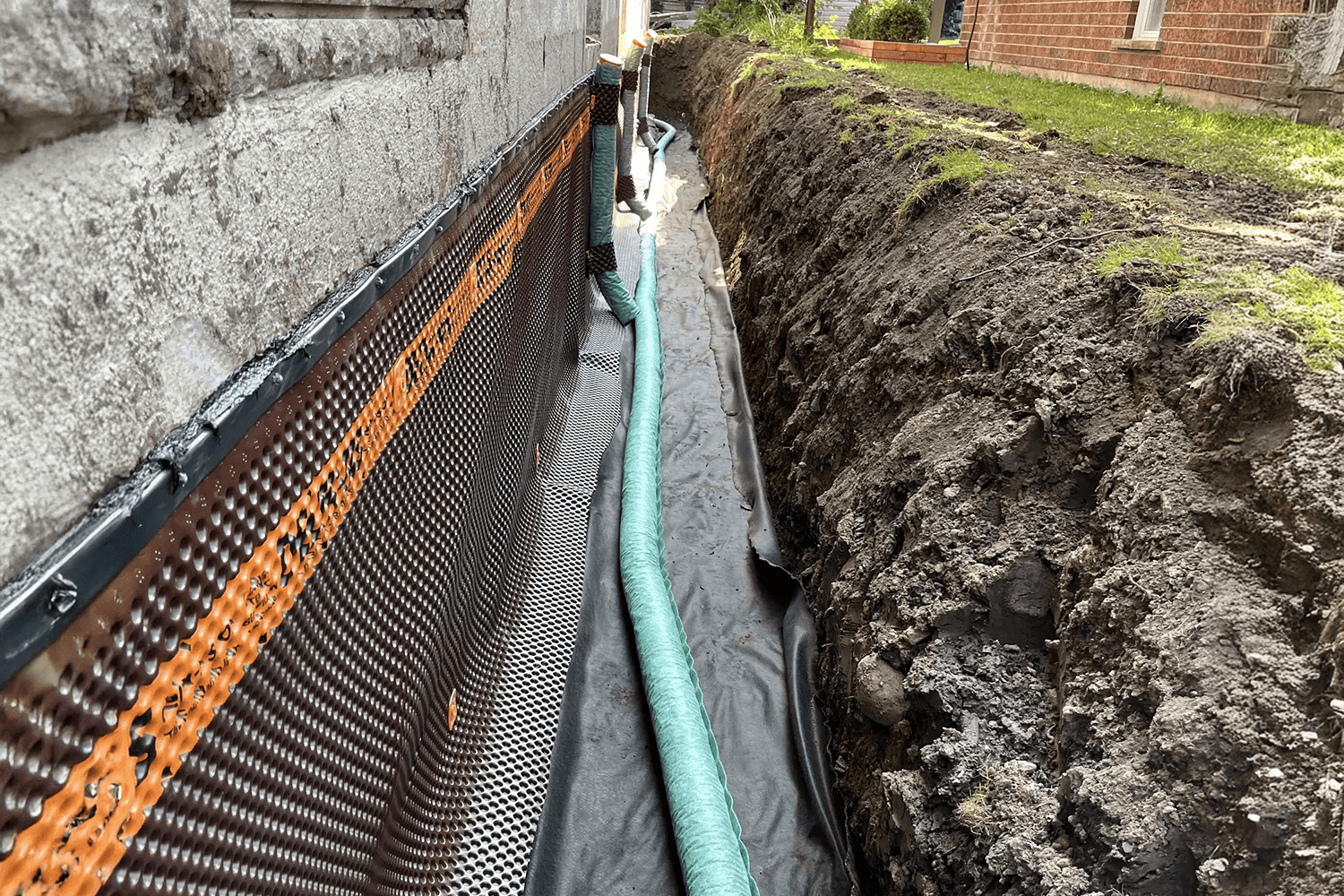  Installation d’un drain français avec membrane d’étanchéité le long des fondations d’une maison.
