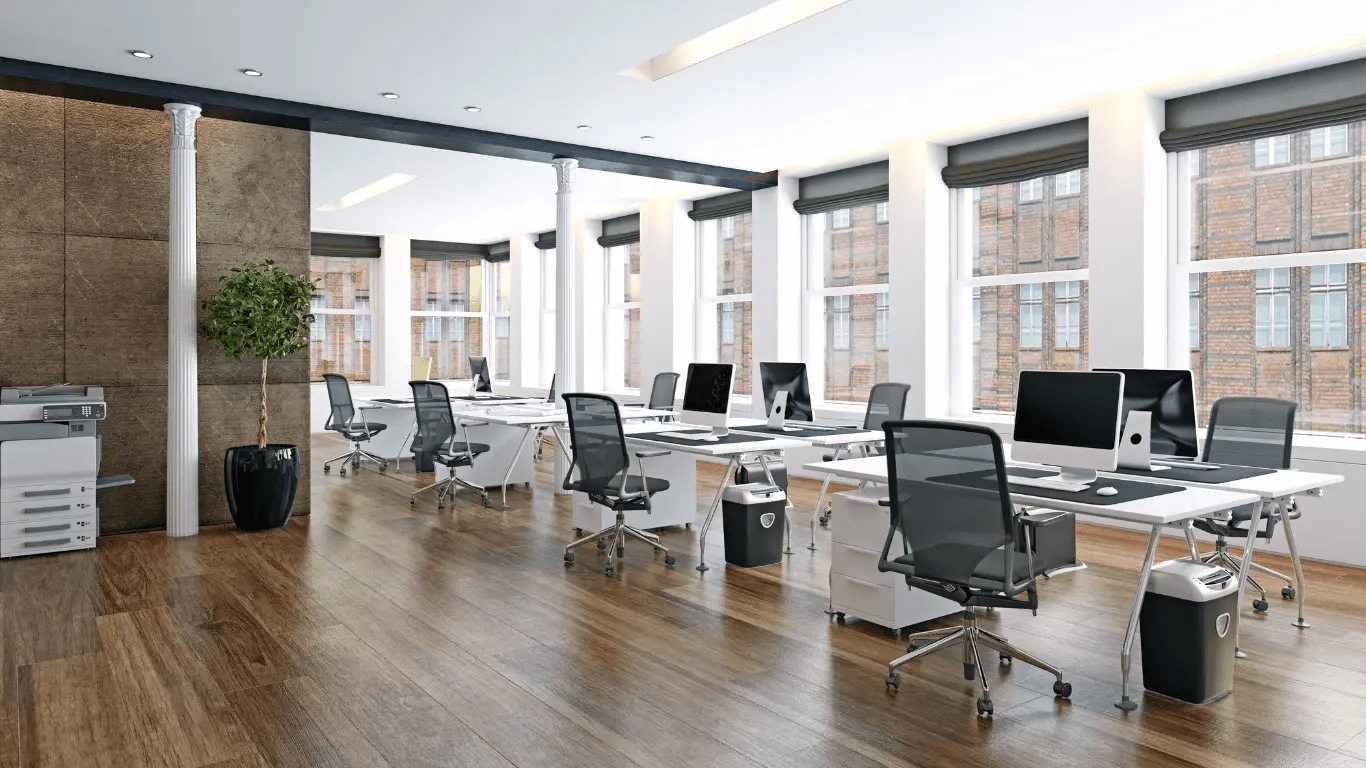 Bureau moderne à aire ouverte avec postes de travail, ordinateurs, fauteuils ergonomiques, grandes fenêtres et plancher de bois