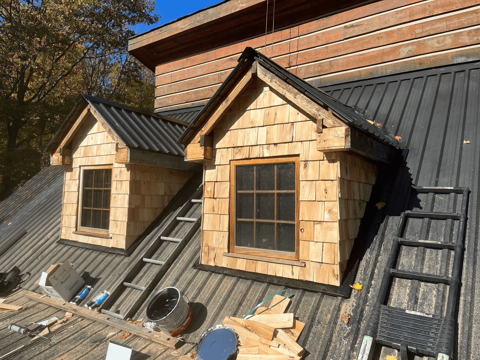 Lucarnes en bois sur une toiture métallique noire dans un projet de rénovation.