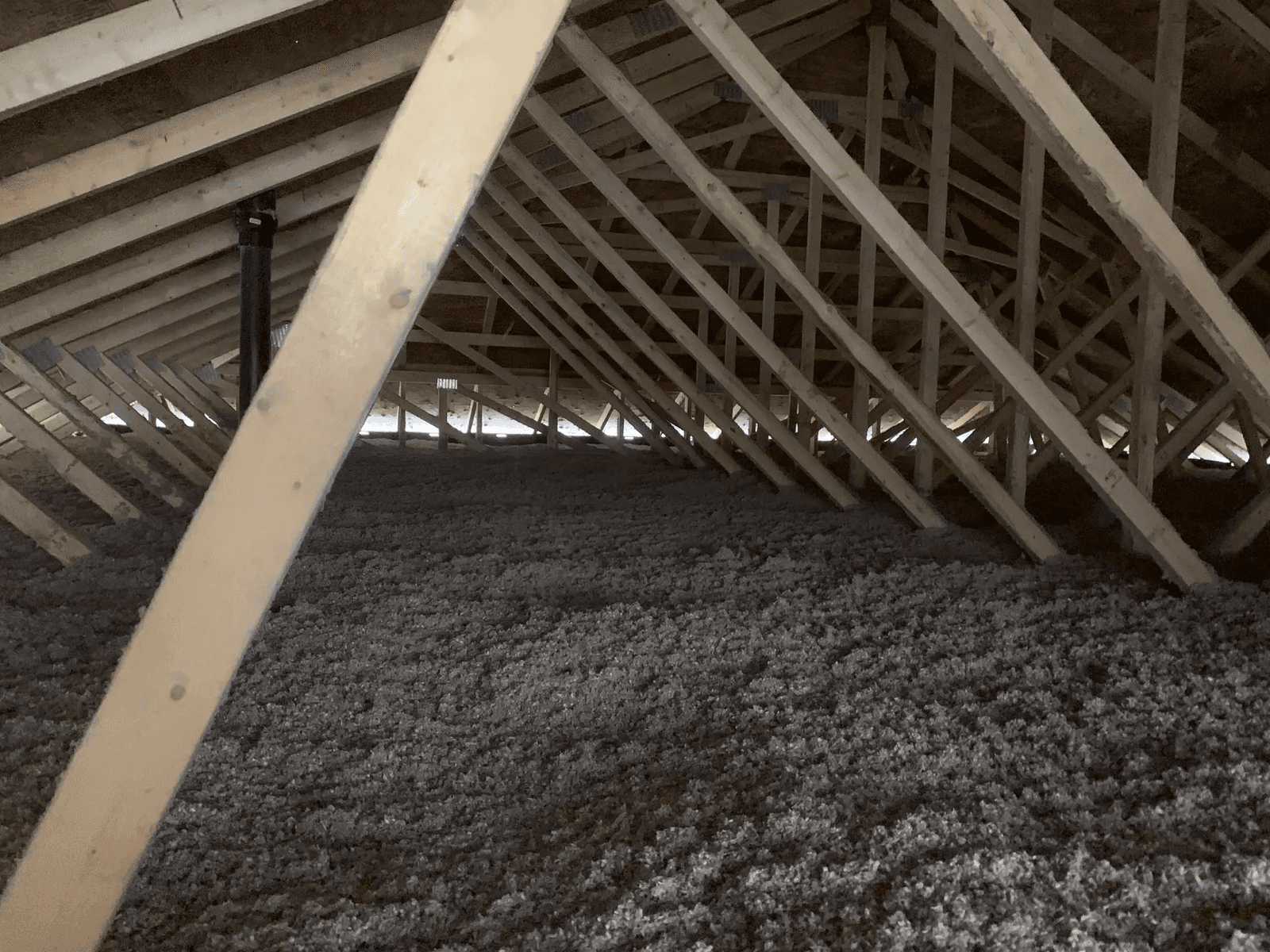 Grenier avec isolation en fibre soufflée et charpente en bois apparente.