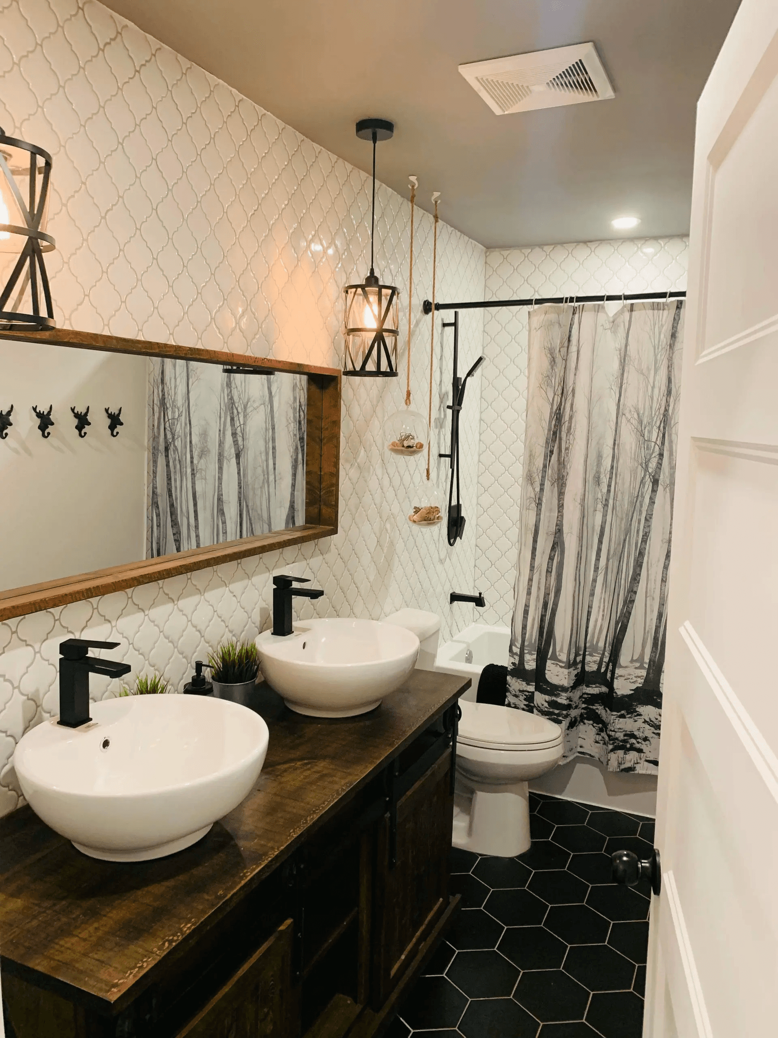Salle de bain rénovée de style rustique moderne avec double lavabo, vanité en bois foncé, céramique murale à motifs et plancher en tuiles hexagonales noires