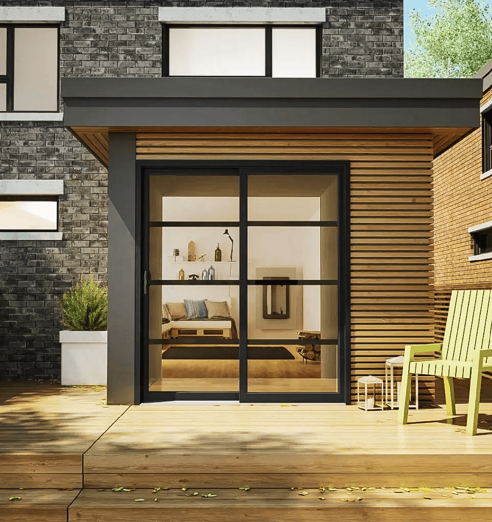 Extension résidentielle moderne avec grande porte vitrée noire, revêtement extérieur en bois horizontal, terrasse en bois et façade contemporaine en brique foncée.