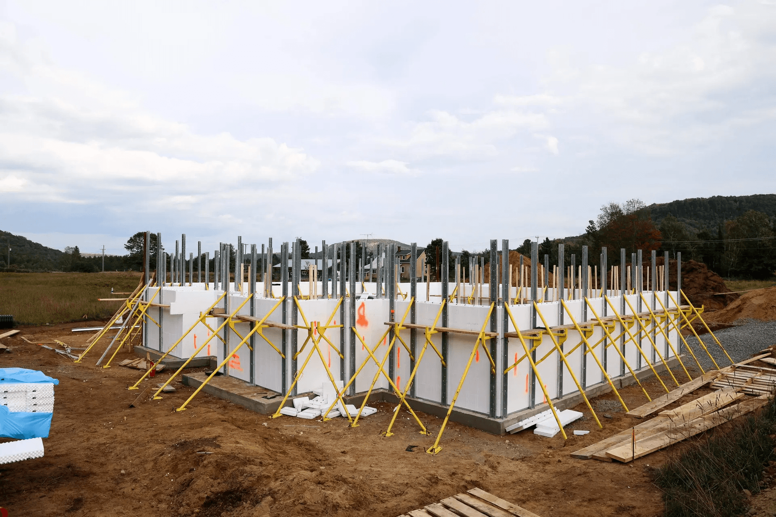 Fondation résidentielle en construction avec coffrage isolant, panneaux modulaires, montants métalliques, étais de stabilisation et préparation structurale pour une nouvelle maison
