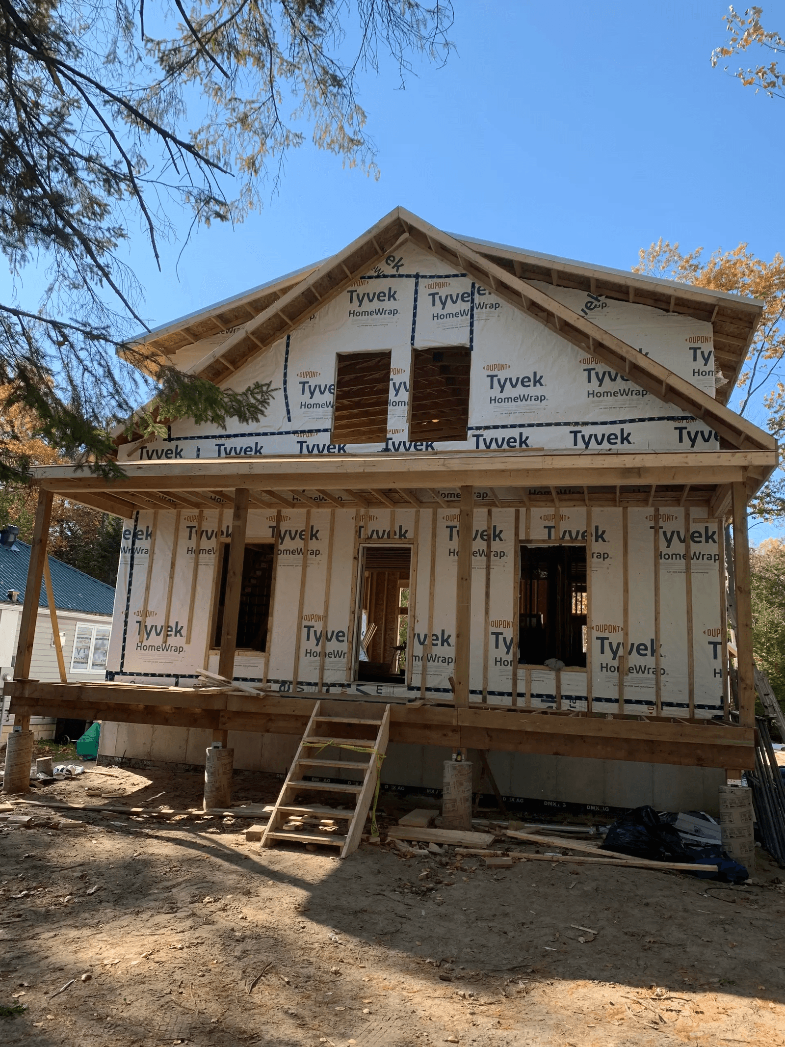 Maison en construction avec charpente en bois et enveloppe de bâtiment sur un chantier résidentiel.