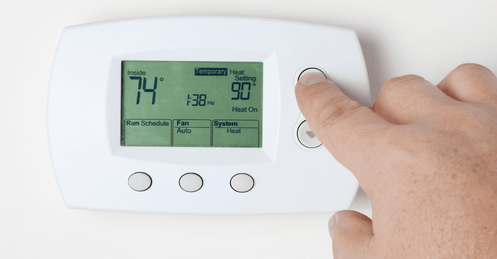 Main ajustant un thermostat numérique pour réguler la température intérieure